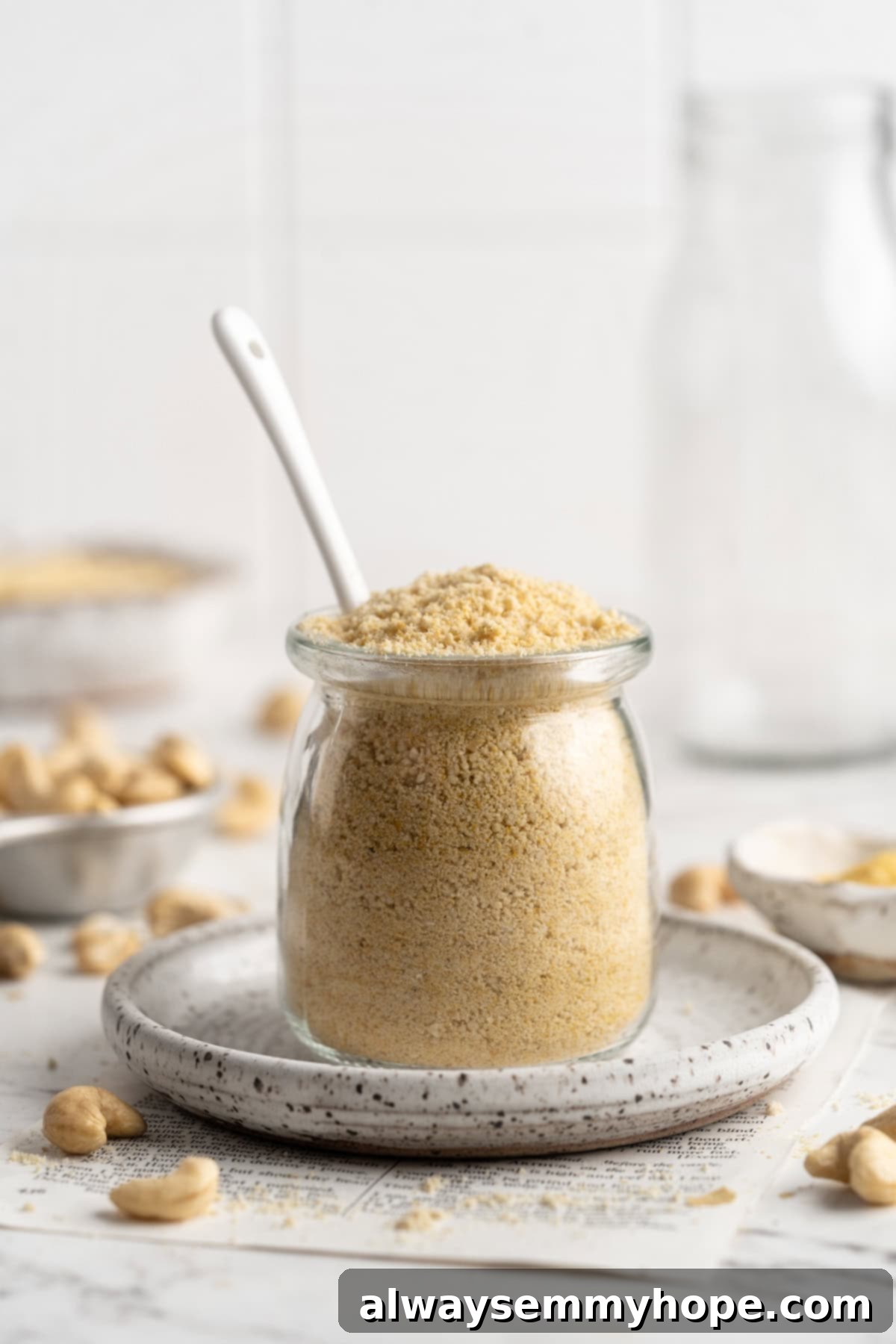This vegan parmesan cheese recipe is quick, easy, and it tastes amazing—and you only need 5 ingredients and 5 minutes to make it! Homemade vegan Parmesan cheese stored in a glass jar with a spoon, highlighting its readiness for long-term use.