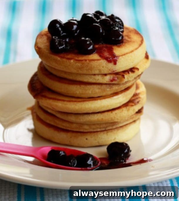 Side shot of a stack of vanilla pancakes with blueberry sauce.