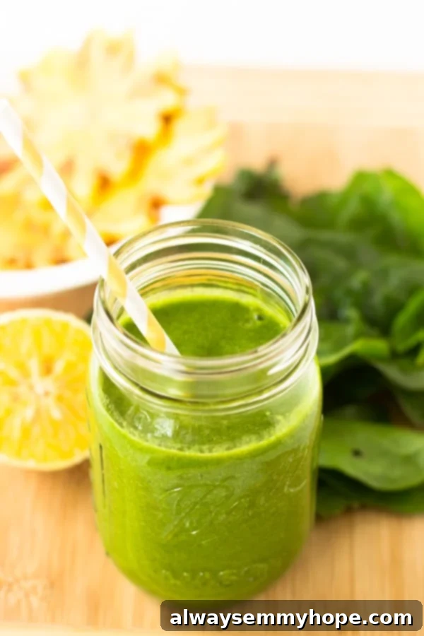 Tropical green smoothie in mason jar on a wood table top. 