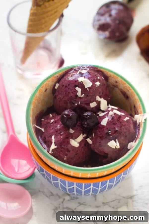 Vibrant purple vegan blueberry ice cream in a colorful bowl with a pink spoon, ready to be enjoyed.