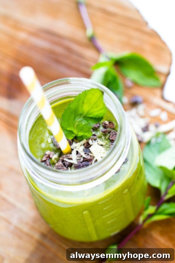 Mint Chocolate Chip Green Dream Smoothie 5 A high-angle shot captures the beautiful green color and inviting texture of the mint chocolate chip green smoothie in a mason jar with a yellow straw, making it look irresistible.