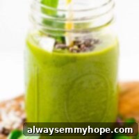 Mint Chocolate Chip Green Dream Smoothie 7 Mint chocolate chip green smoothie in a mason jar with a straw and sprig of mint.