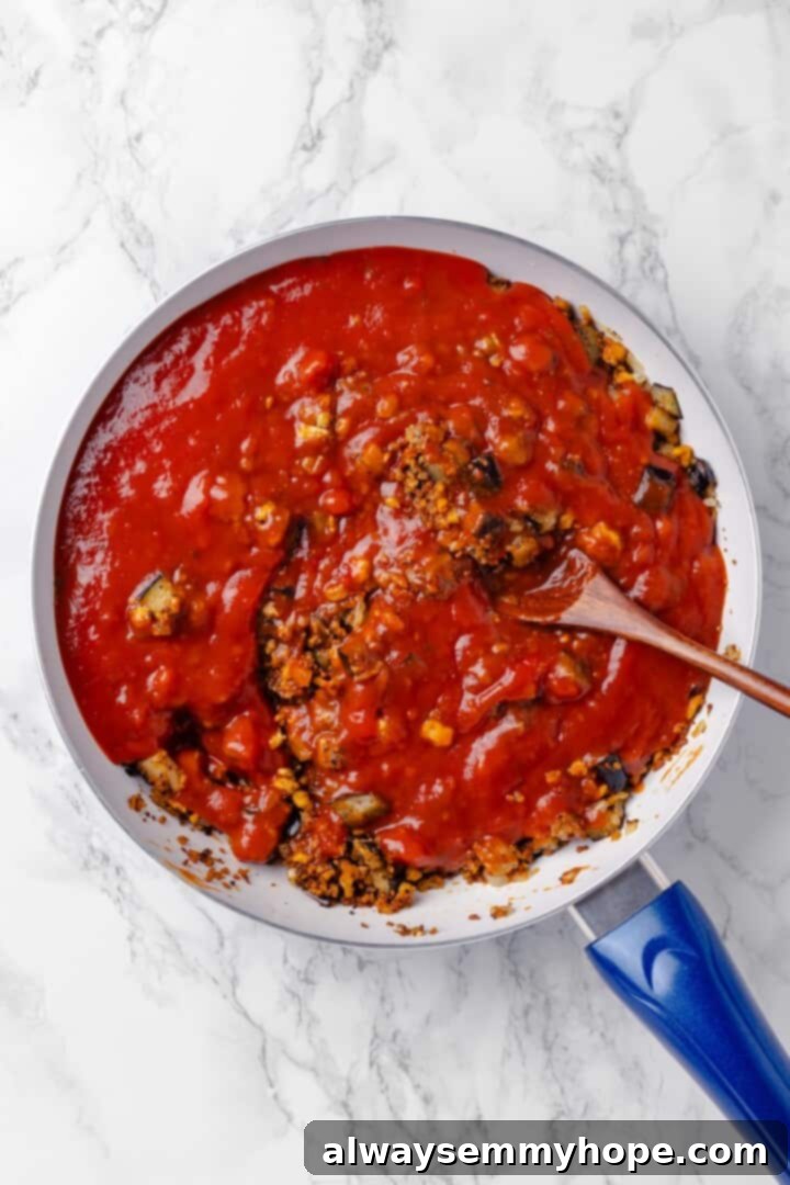 Stirring tomato sauce into vegan ground meat mixture