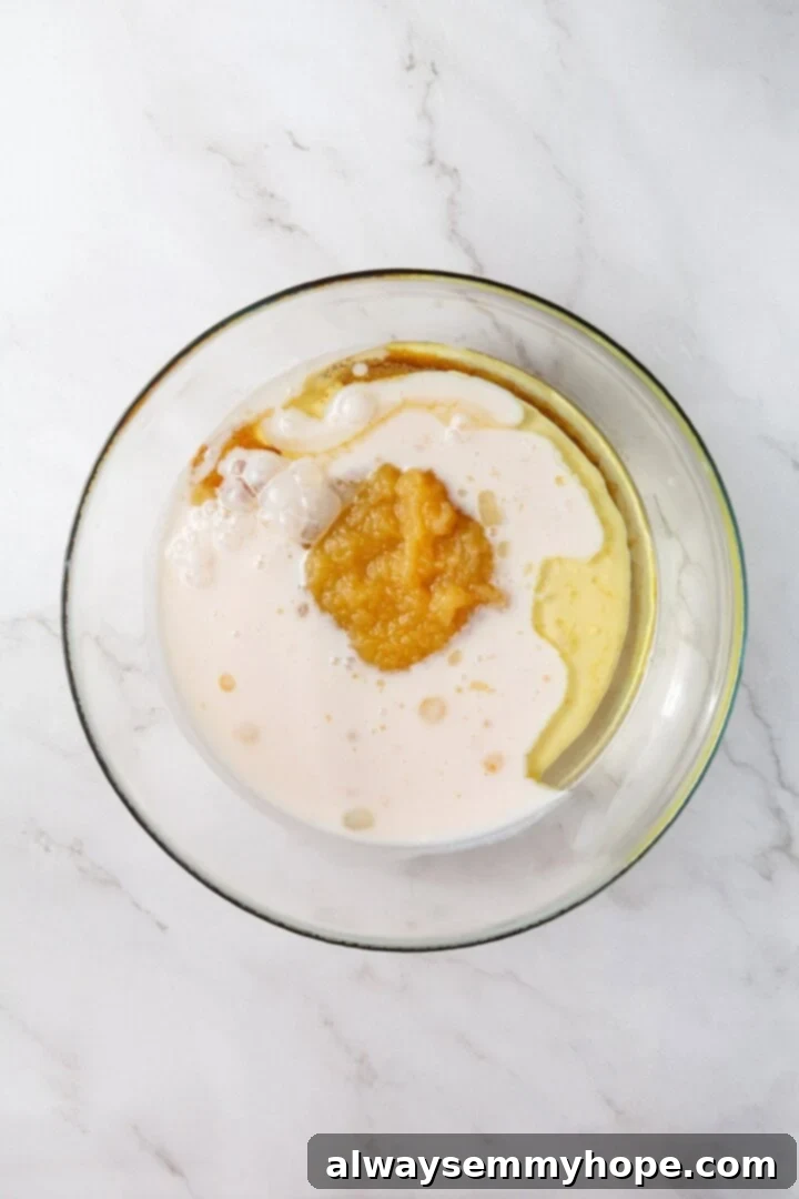 Wet ingredients for vegan muffins in glass bowl before mixing.