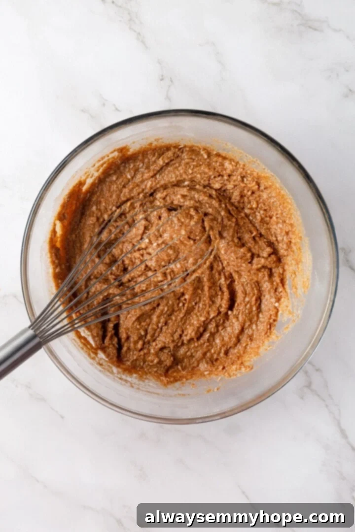 Whisking batter for morning glory muffins in bowl.