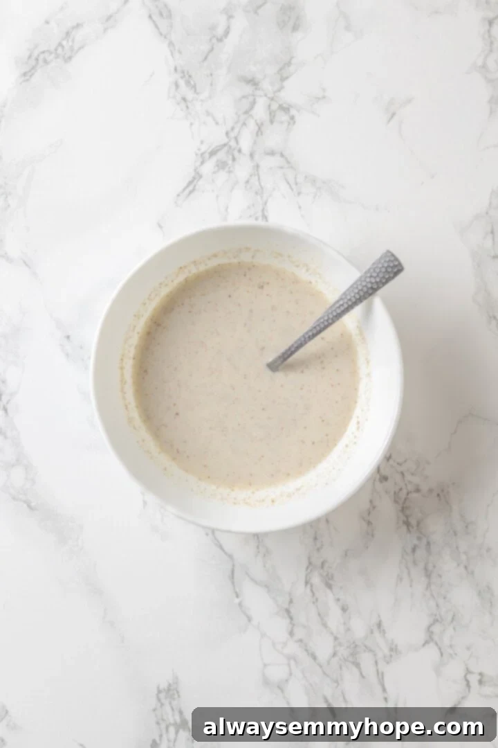 Flax and milk mixture in bowl with spoon.