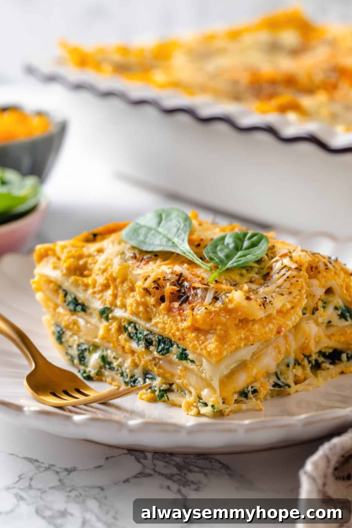 A single slice of butternut squash lasagna on a plate, invitingly displayed with a fork, ready to be savored.