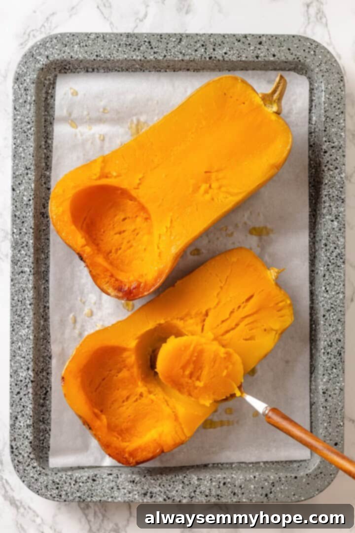 Spoon scooping the flavorful flesh from roasted butternut squash, ready to be pureed into a creamy filling.