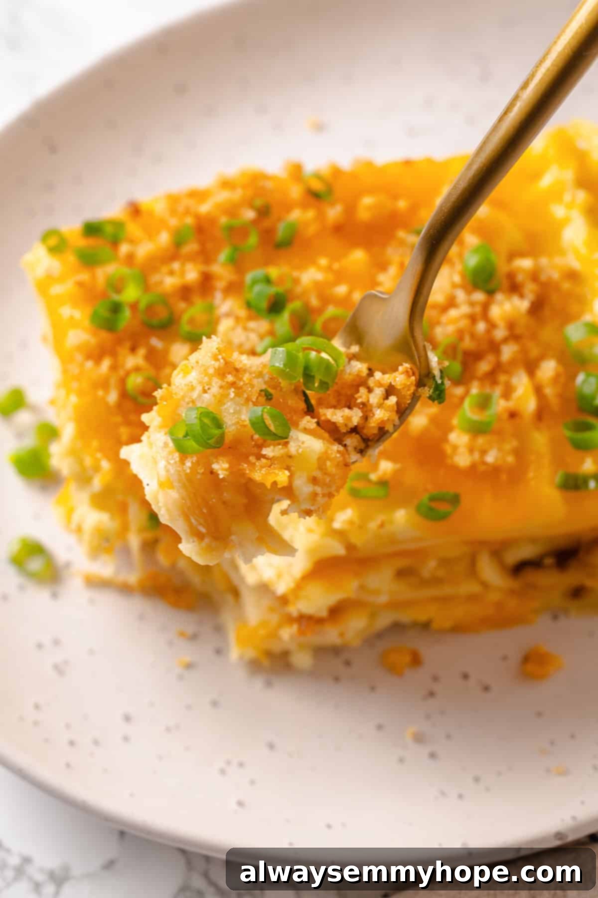 Forkful of vegan pierogi casserole held over a plate.
