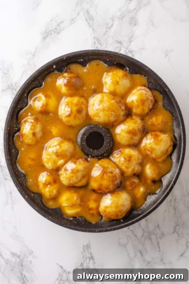 Vegan monkey bread dough in a bundt pan before baking, with the caramel mixture poured evenly over the dough balls.