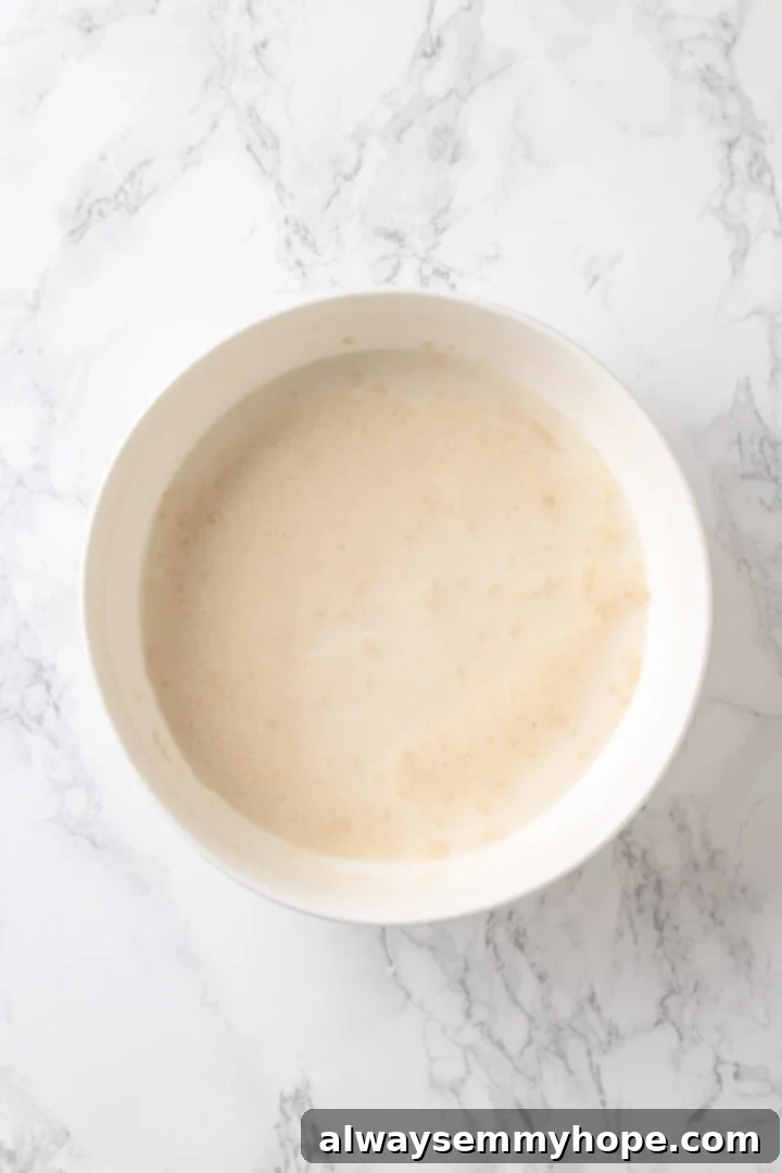 Warm vegan milk and yeast being mixed in a bowl to activate the yeast for the monkey bread dough.