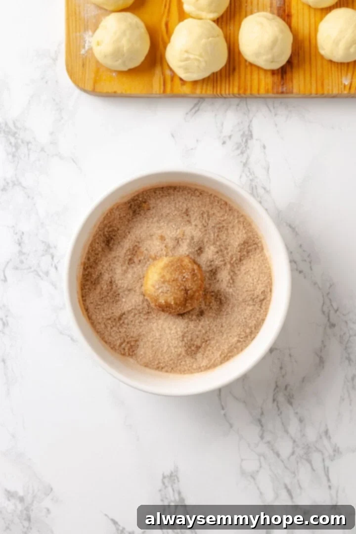 A ball of vegan monkey bread dough being dipped into a mixture of melted vegan butter and then rolled in cinnamon sugar.