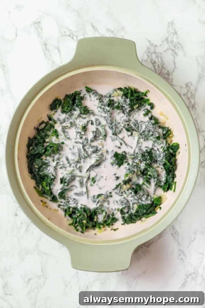 Cashew cream added to spinach in a skillet.