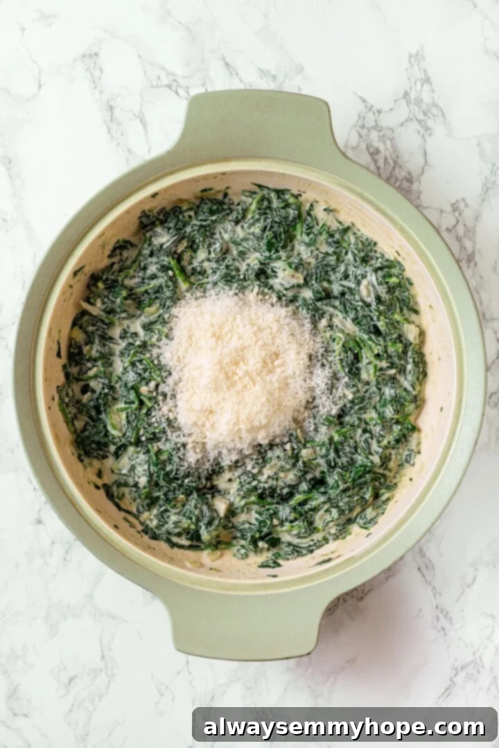 Vegan Parmesan cheese added to creamed spinach in a skillet.