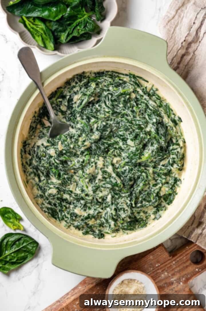 Spoon in skillet of creamed spinach.