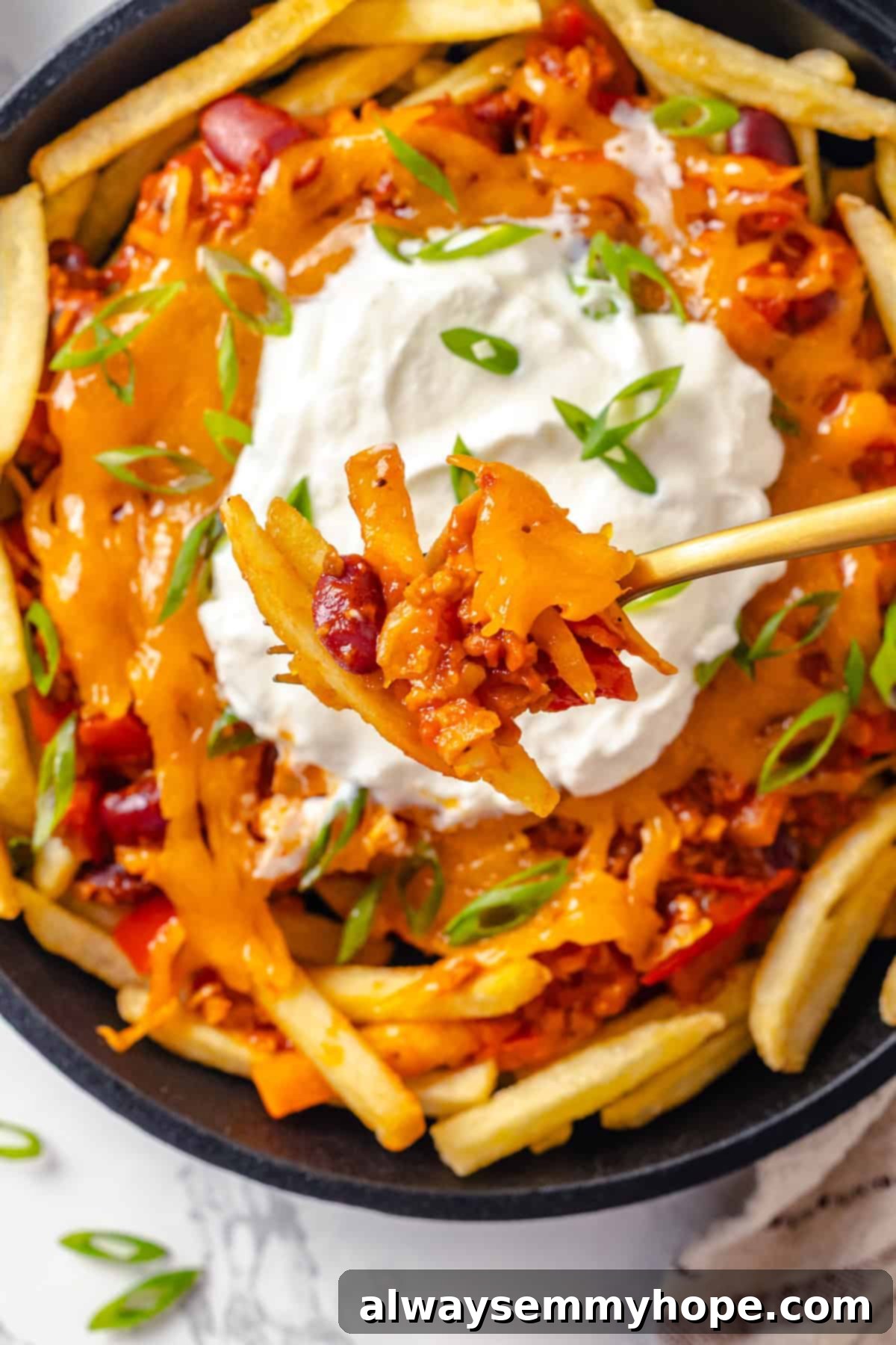 Forkful of chili cheese fries held over skillet