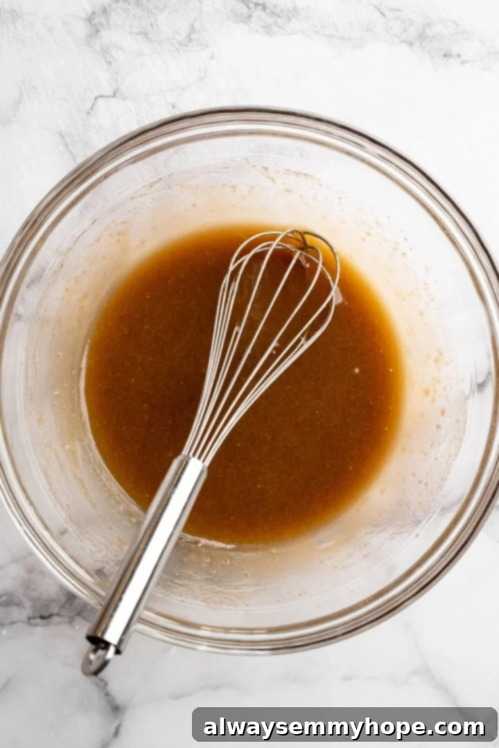 Wet ingredients mixed in glass bowl with whisk.