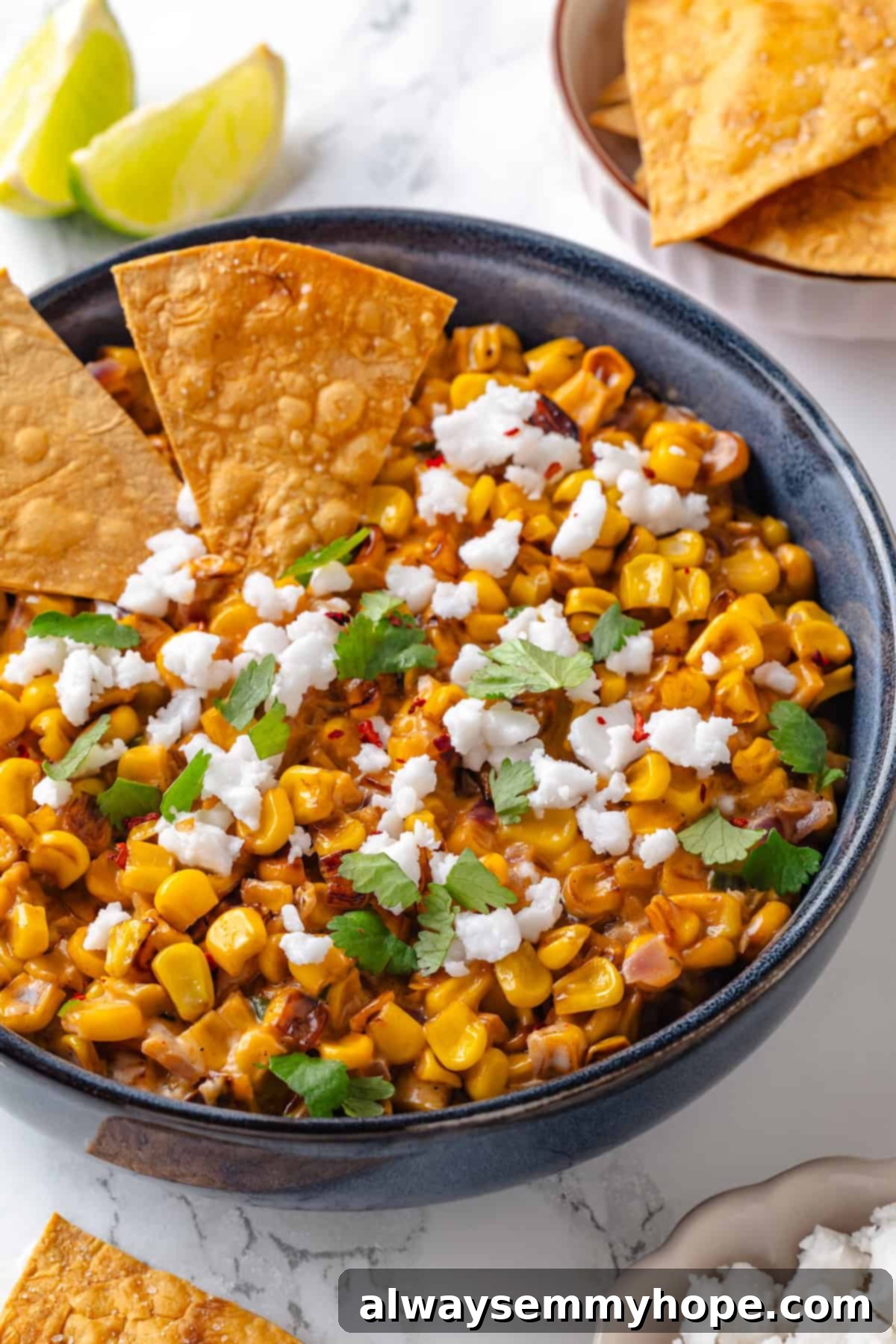 Two tortilla chips in a bowl of Vegan Mexican Street Corn Dip