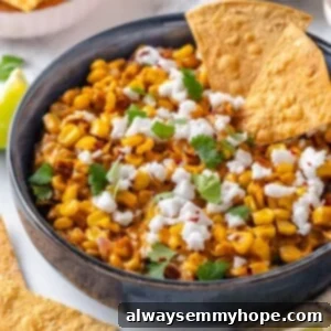 Bowl of Mexican street corn dip with two tortilla chips.