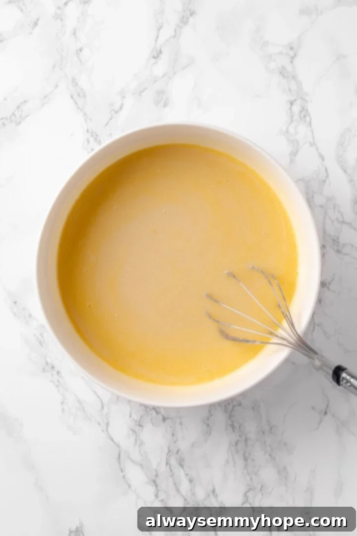 Wet ingredients for vegan chocolate chip muffins in a bowl with a whisk