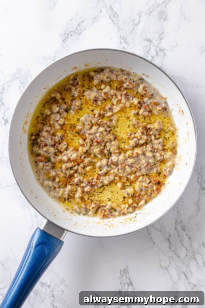 Garlic butter sauce in skillet with walnuts.