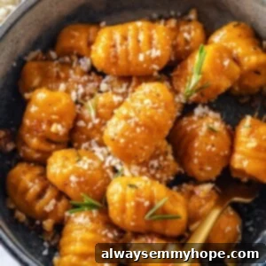 Bowl of sweet potato gnocchi with vegan parmesan and rosemary.