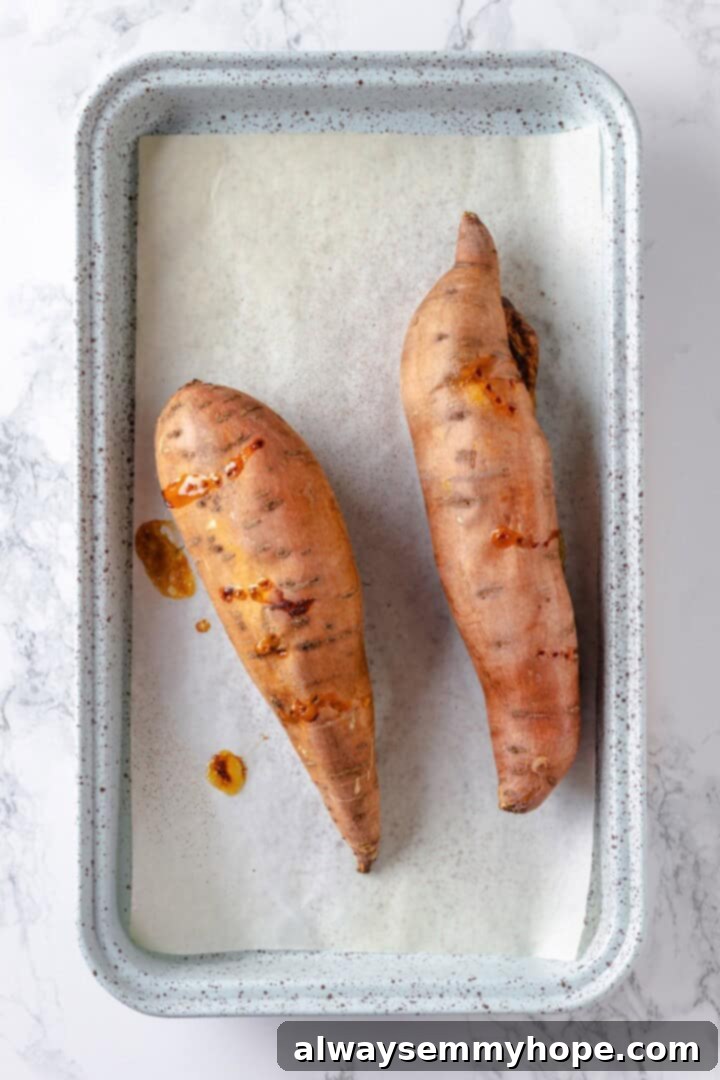 Two roasted sweet potatoes on sheet pan.
