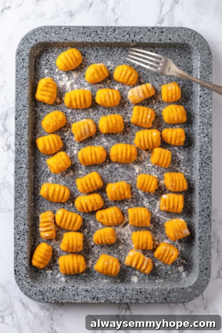 Homemade sweet potato gnocchi on sheet pan with fork.
