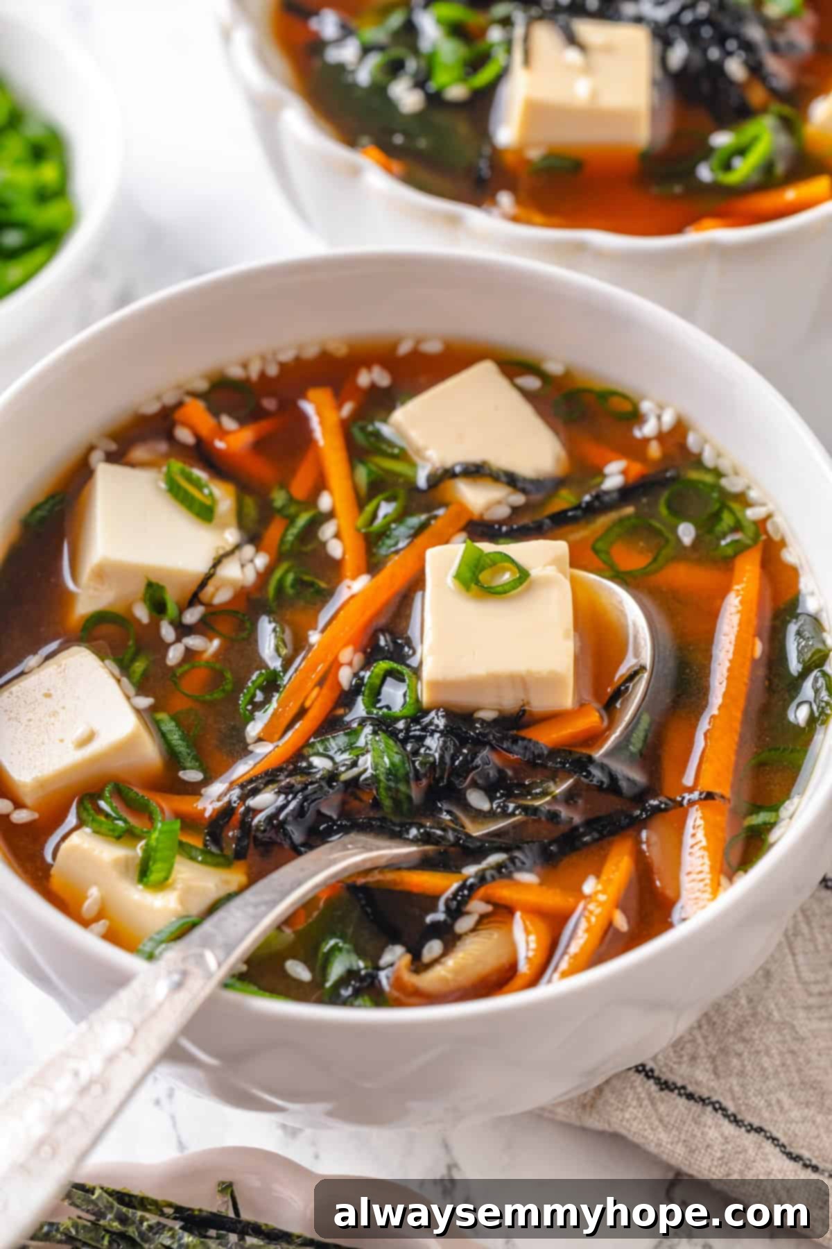 Spoonful of vegan miso tofu soup in bowl.