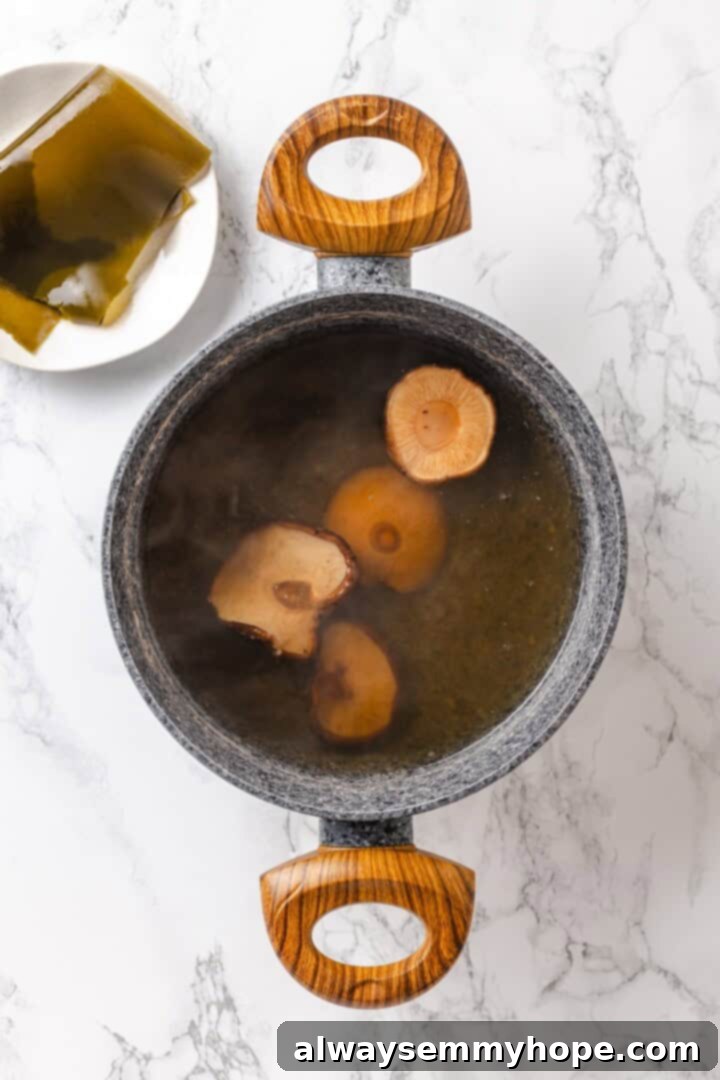 Shiitake mushrooms soaking in pot of broth set next to plate of kombu.
