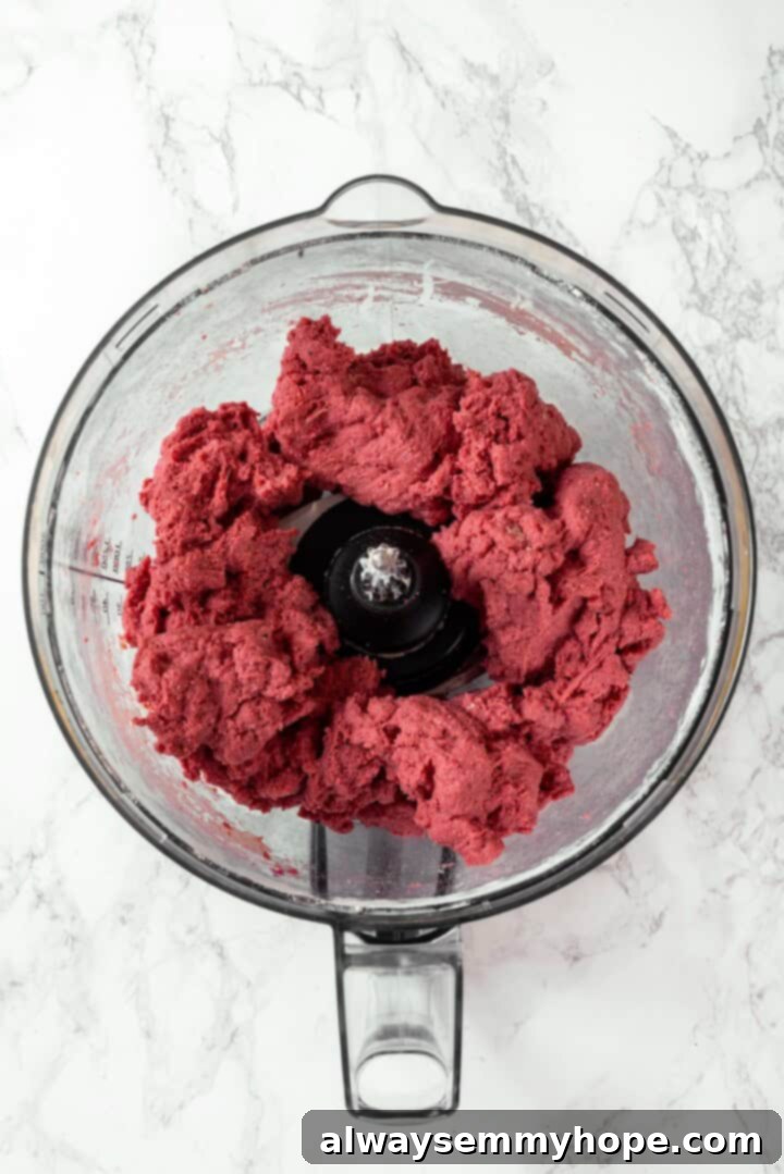 Red salami dough being processed in a food processor until smooth and cohesive.