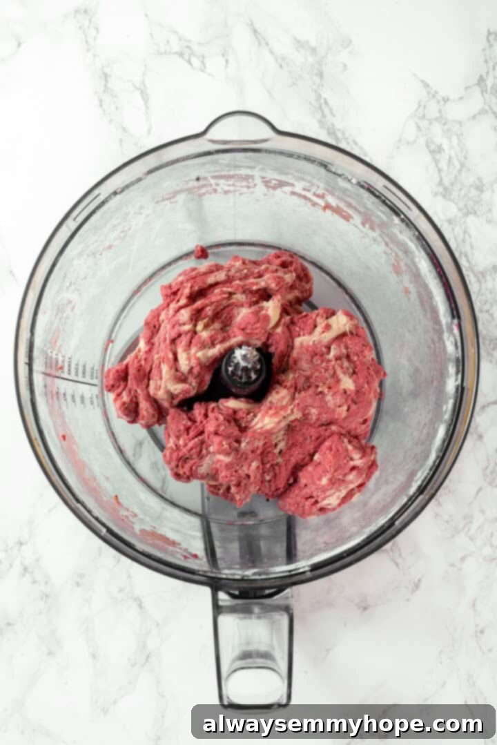 The red and white salami dough being gently combined in a food processor to create a marbled effect.