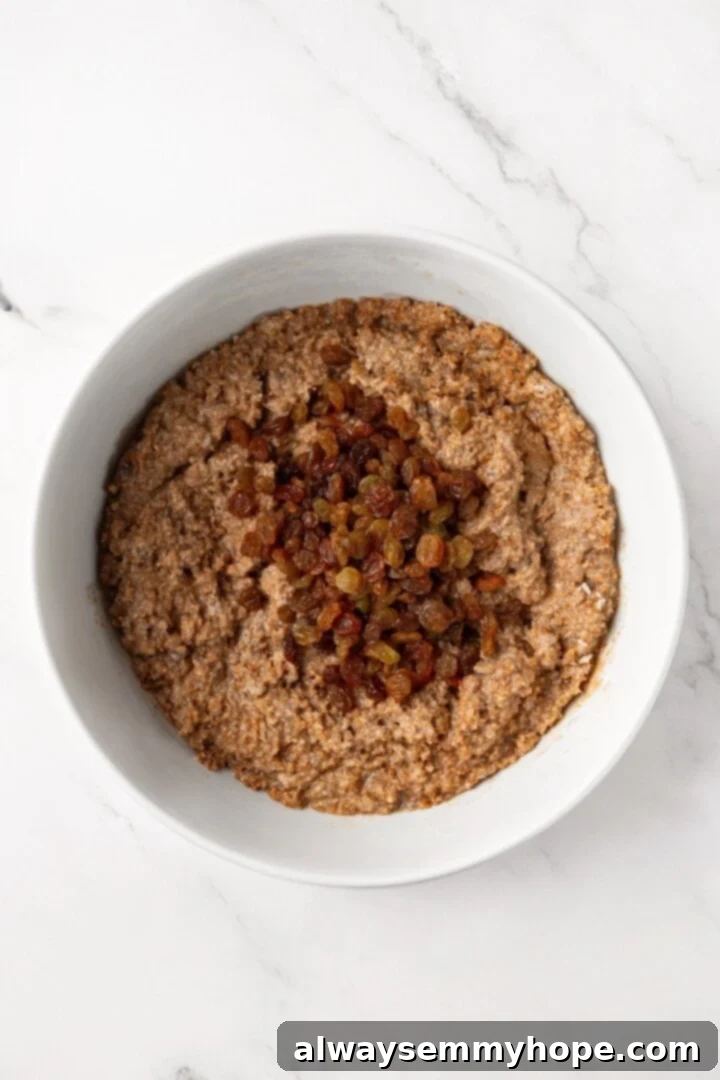 Golden raisins being added to the vegan bran muffin batter.