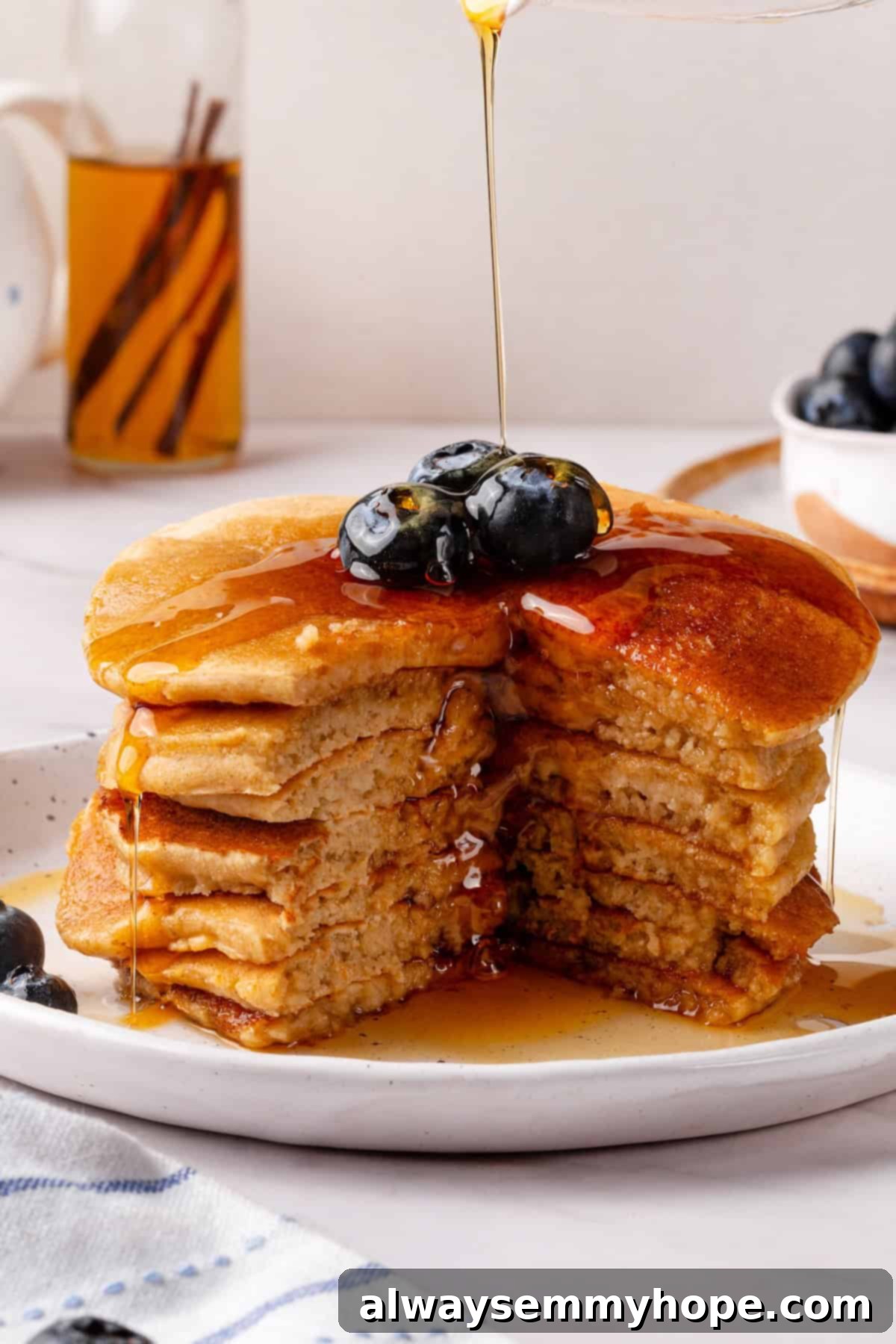 Drizzling maple syrup over a tempting stack of oat flour pancakes.