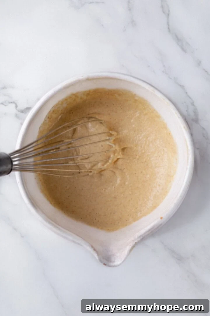 Whisking oat flour pancake batter in a mixing bowl.