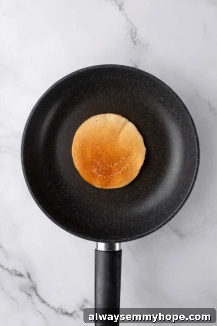 Oat flour pancake cooking in a skillet.