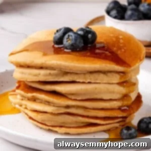 Stack of oat flour pancakes topped with blueberries and syrup.