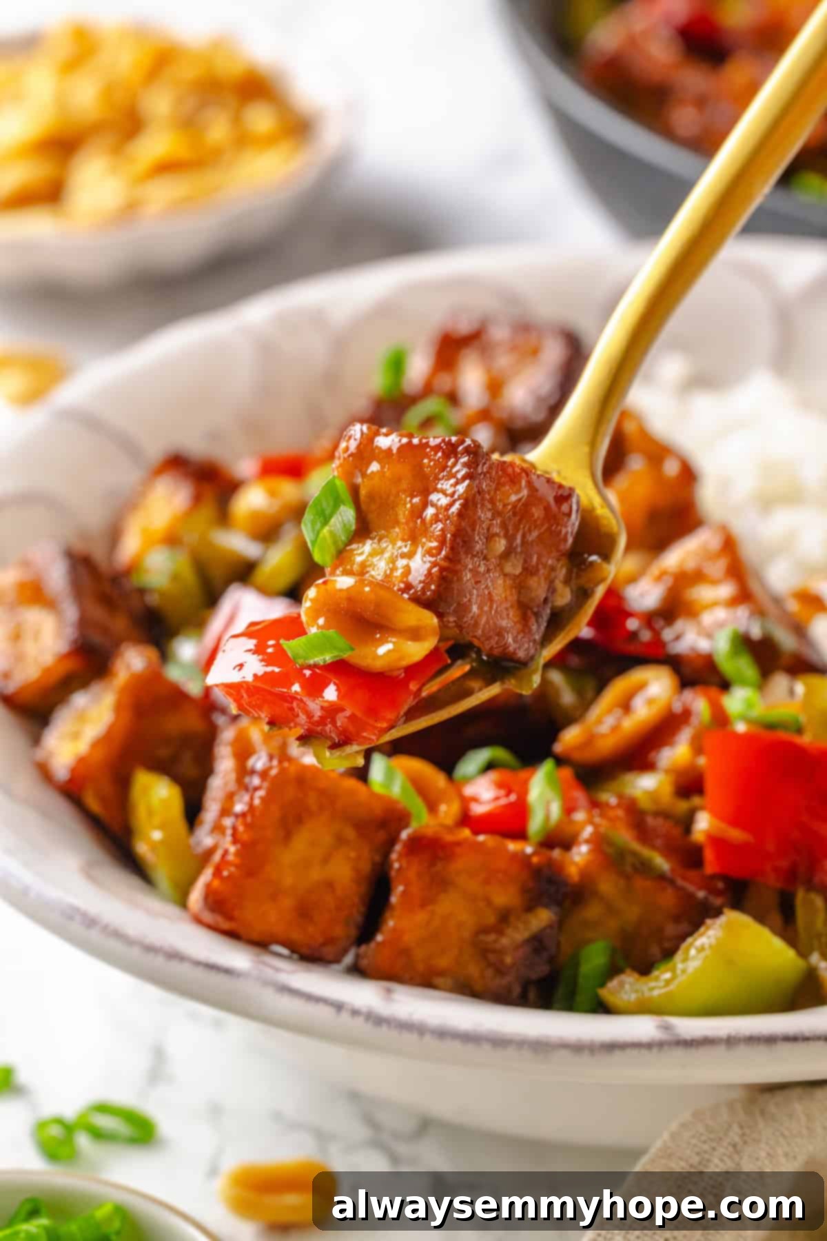 Forkful of Kung Pao Tofu held over a bowl
