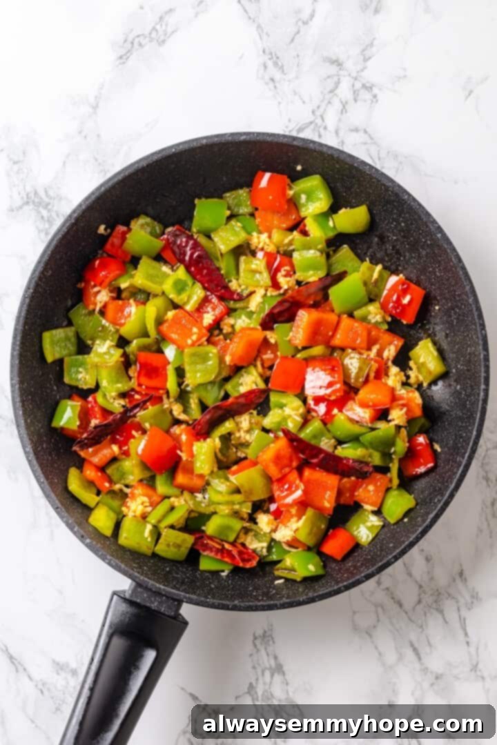 Bell peppers cooking in a skillet with chili peppers
