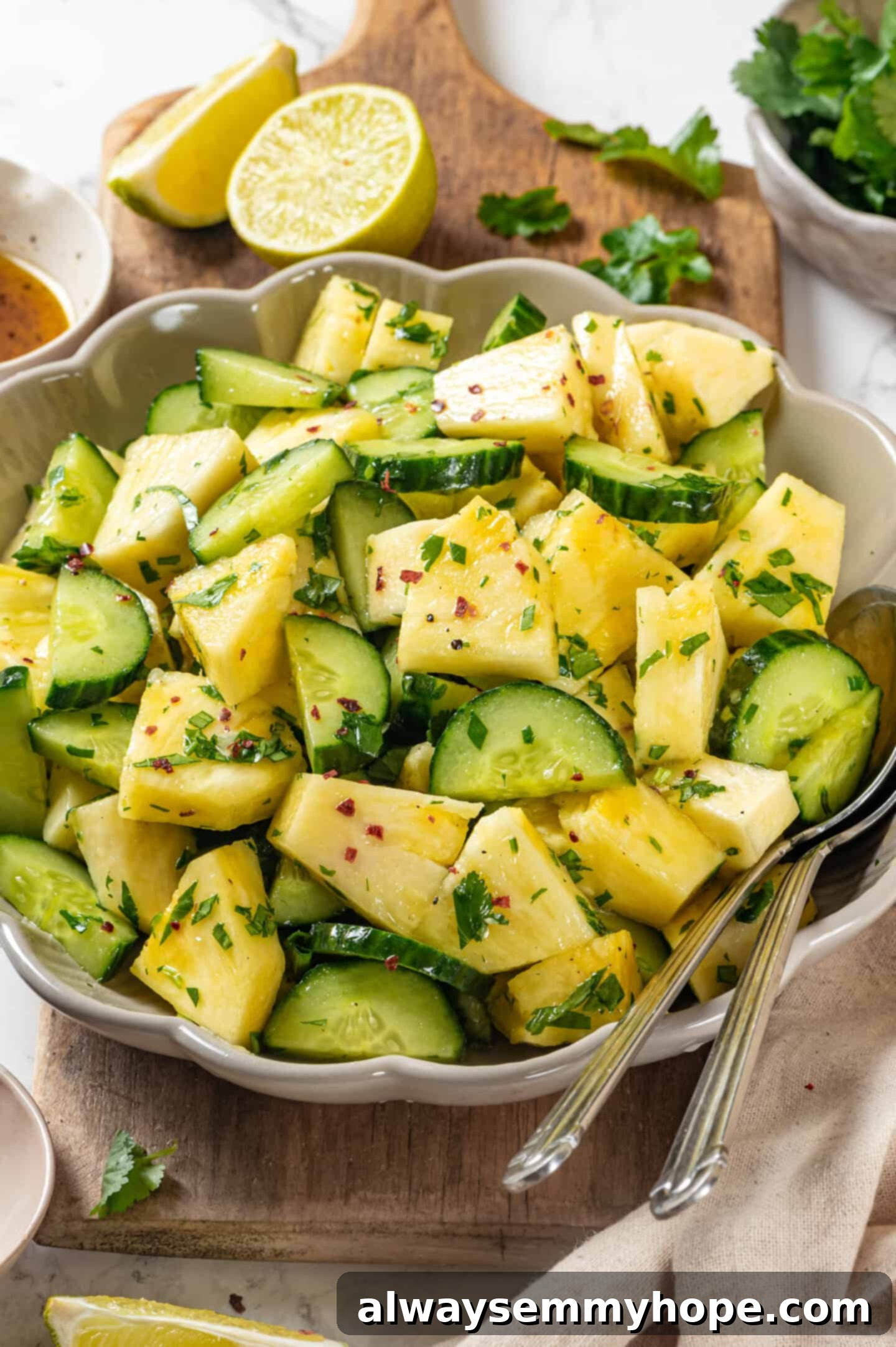 Pineapple Cucumber Refresher 2 Pineapple cucumber salad in a bowl with two spoons, showcasing its vibrant colors and textures.