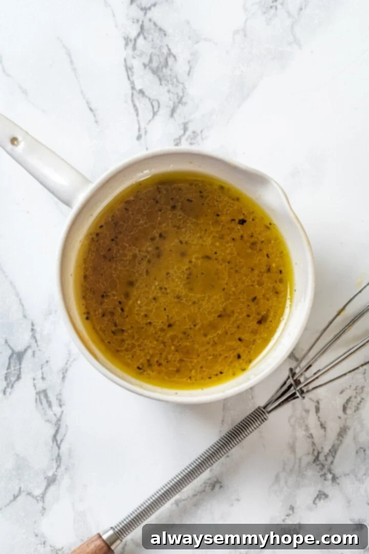 Pineapple Cucumber Refresher 5 Lime vinaigrette in a small bowl, next to a whisk, ready to dress the salad.