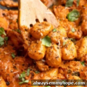 Wooden slotted spoon stirring cheesy tomato gnocchi