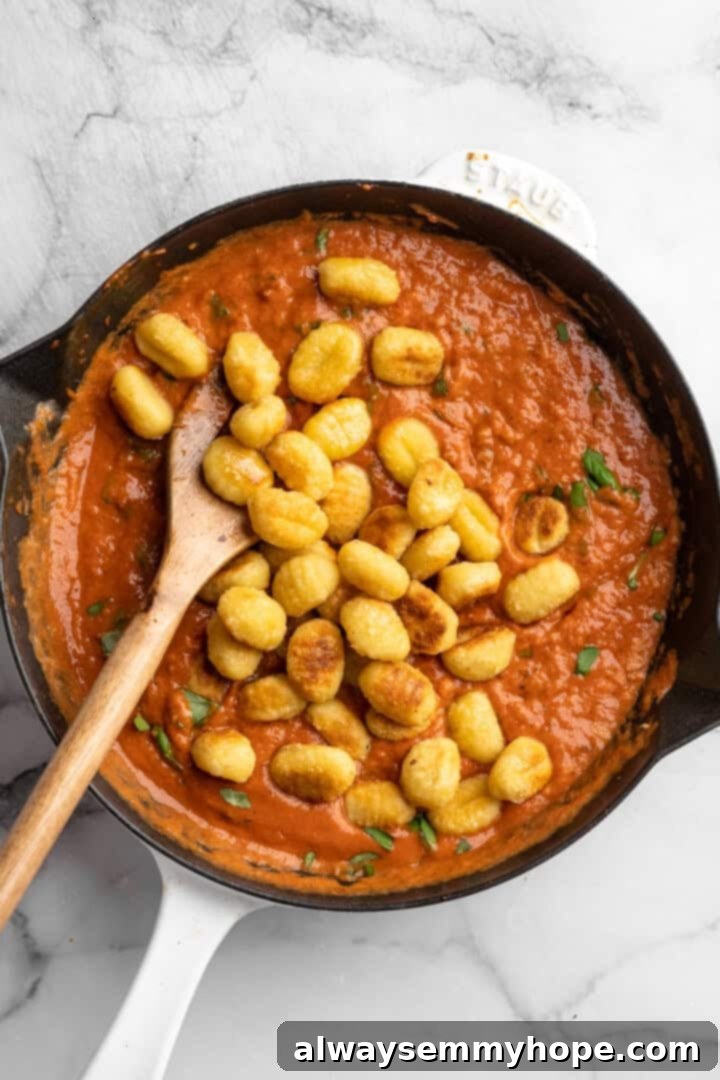 Stirring toasted gnocchi into skillet of creamy tomato sauce