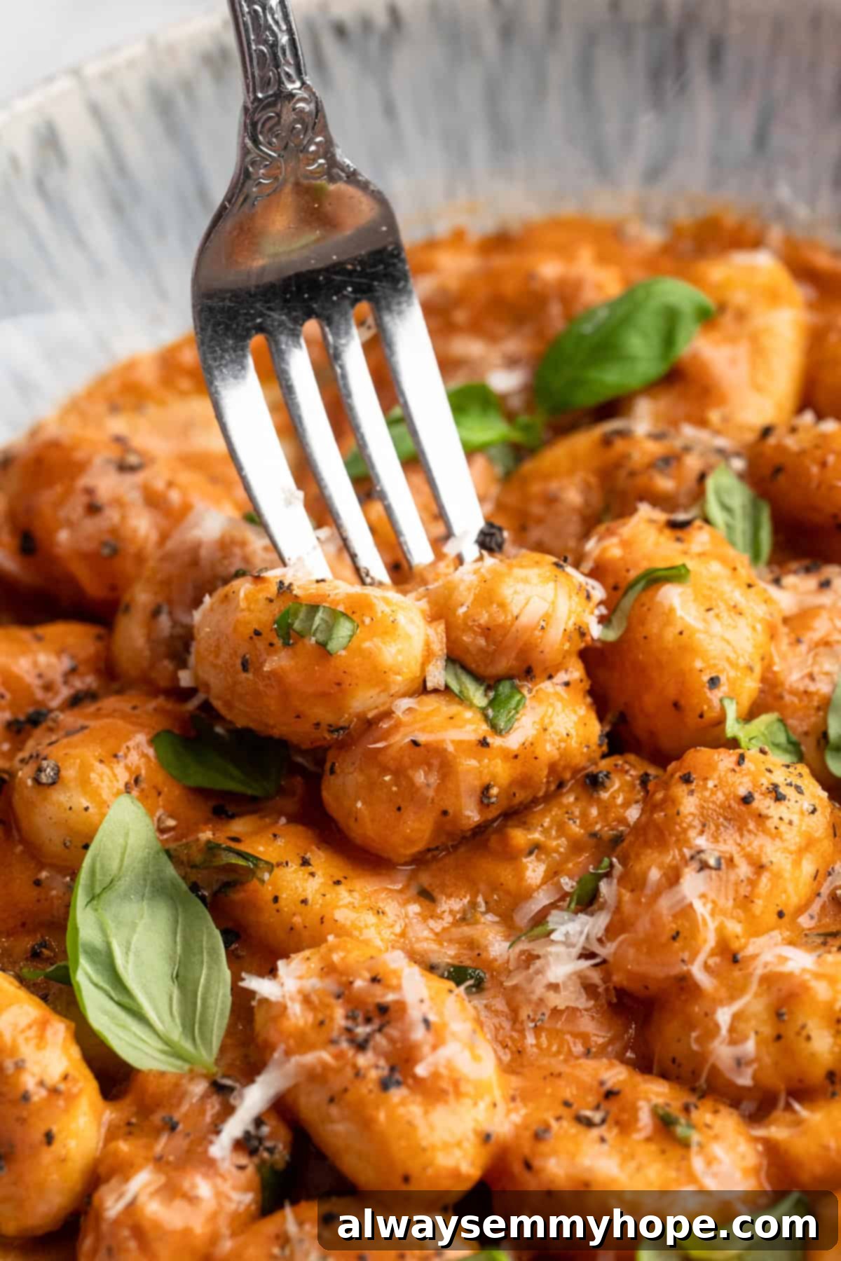 Fork piercing cheesy tomato gnocchi in bowl