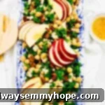 Overhead view of kale apple salad topped with chickpeas and vegan feta on a rectangular platter.